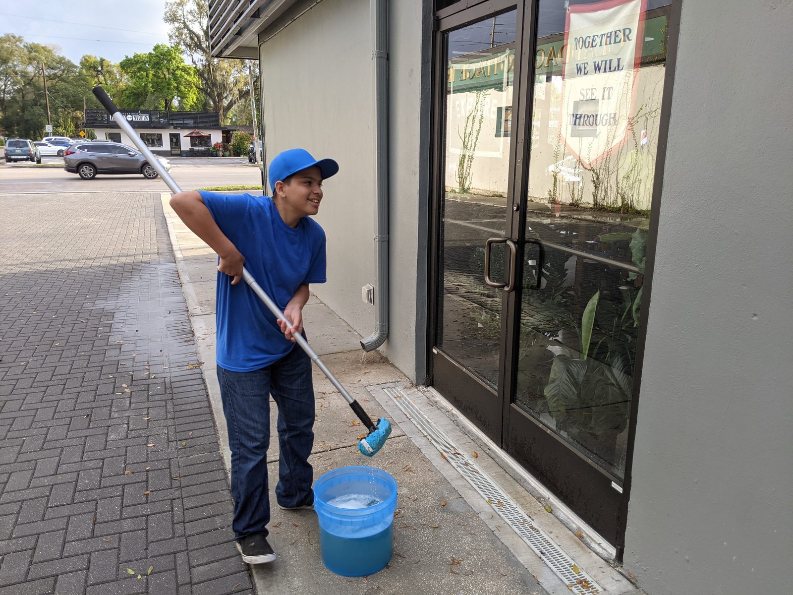 One of Andy&rsquo;s sons cleaning a storefront window with a water-fed pole
